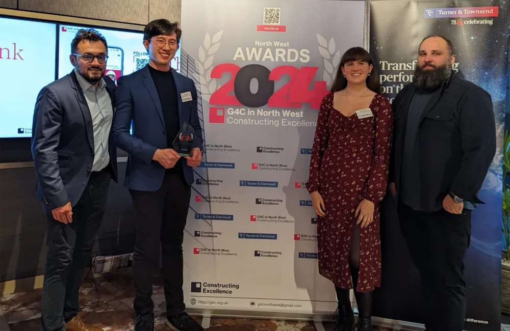 Jerryl holding the award standing with three other people in front of a North West Awards 2024 banner