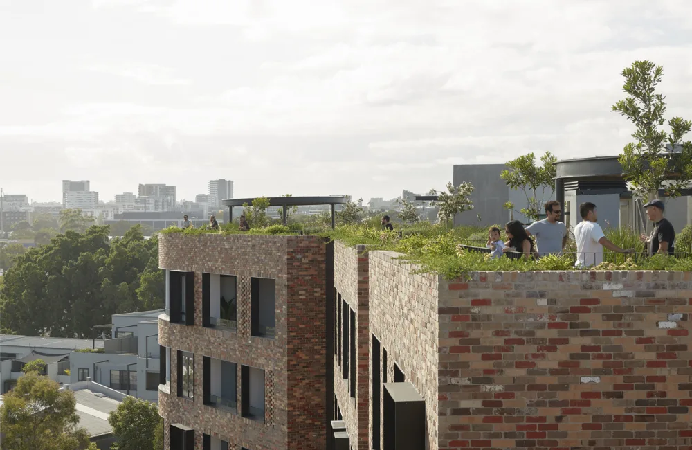 People enjoying green spaces on the flat roofs of a curved residential brick building