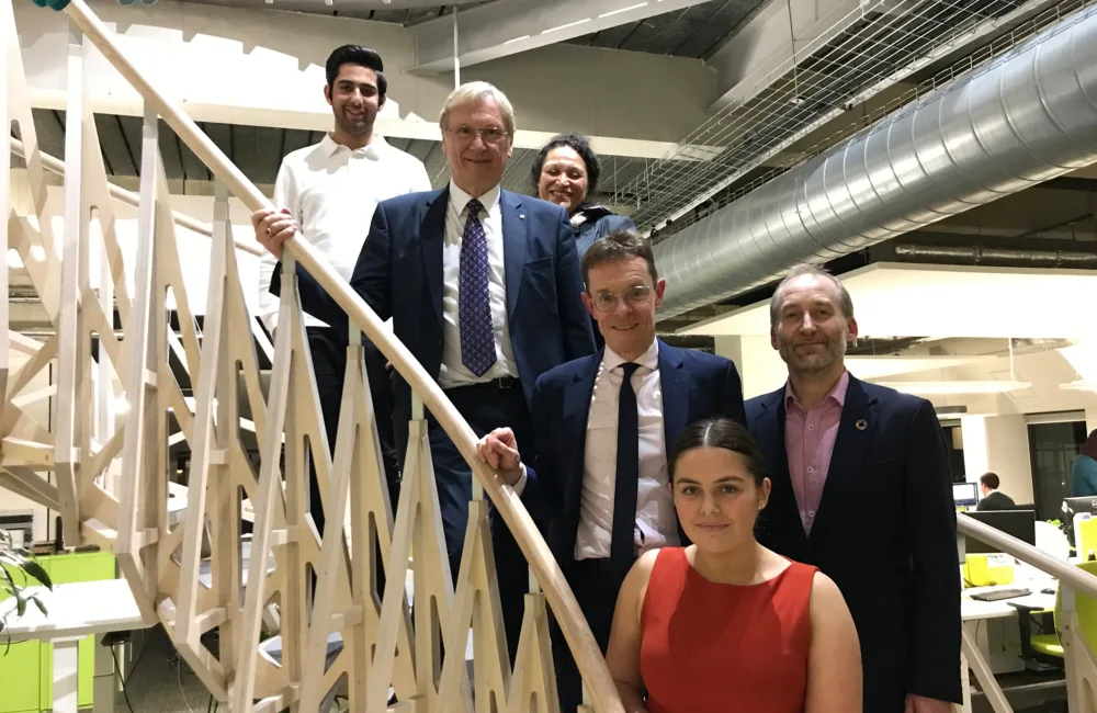 Six smiling people standing on the wooden spiral stairs on the Cundall Birmingham office