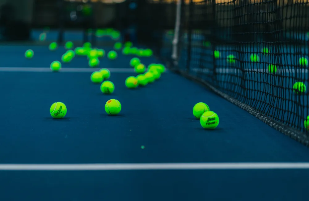 Fluorescent green tennis balls sitting on a dark blue tennis court