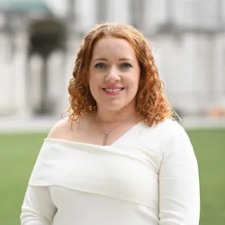 Yvonne McNally with white building and grass background
