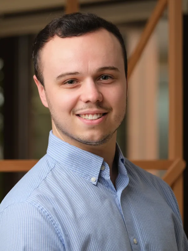 Ben wearing a blue shirt standing against a blurred background