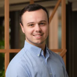 Ben wearing a blue shirt standing against a blurred background