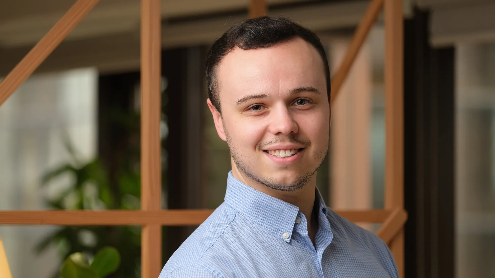 Ben wearing a blue shirt standing against a blurred background
