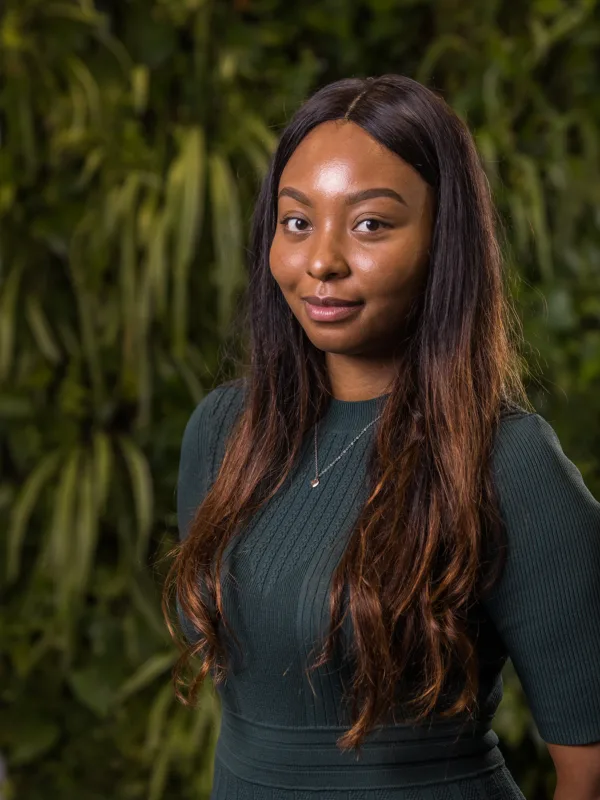 Brittany Huggins in a dark green top in front of a green living wall