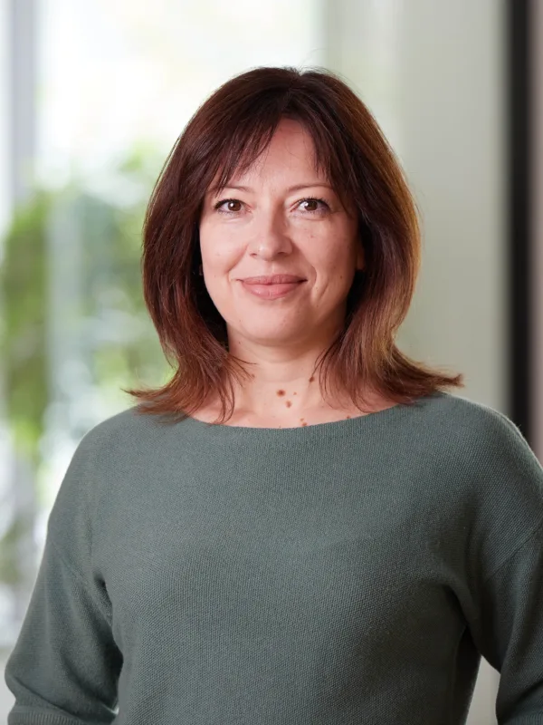 Natalia in a green top stood smiling to camera with a blurred office background