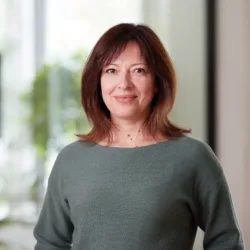Natalia in a green top stood smiling to camera with a blurred office background
