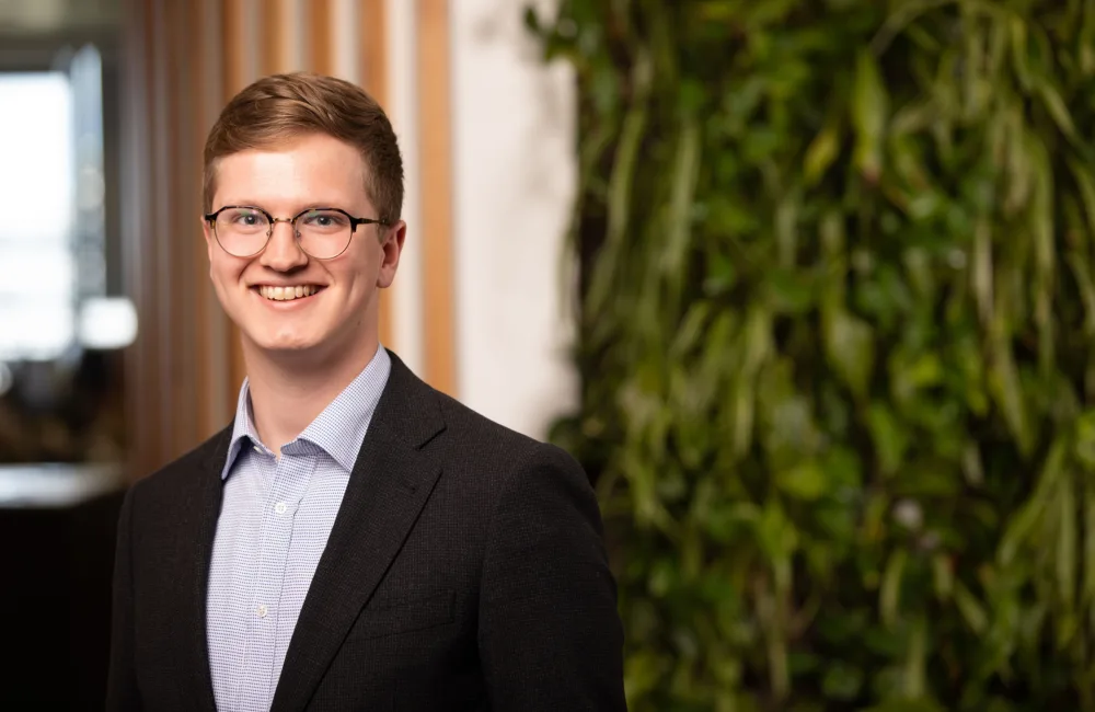 Tim in a blue shirt and suit jacket in front of a living wall