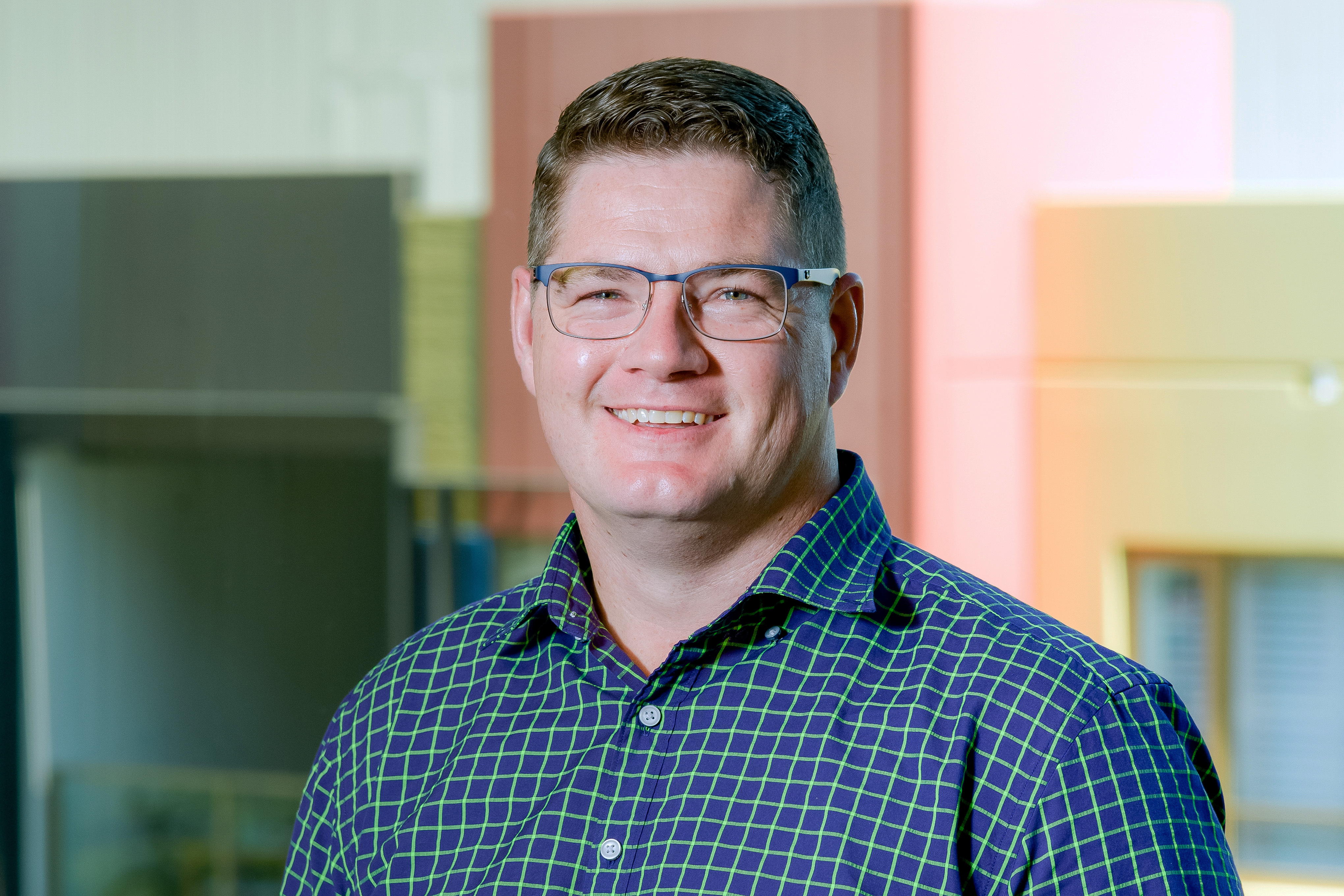Dave in a dark blue checked shirt, outside smiling to camera