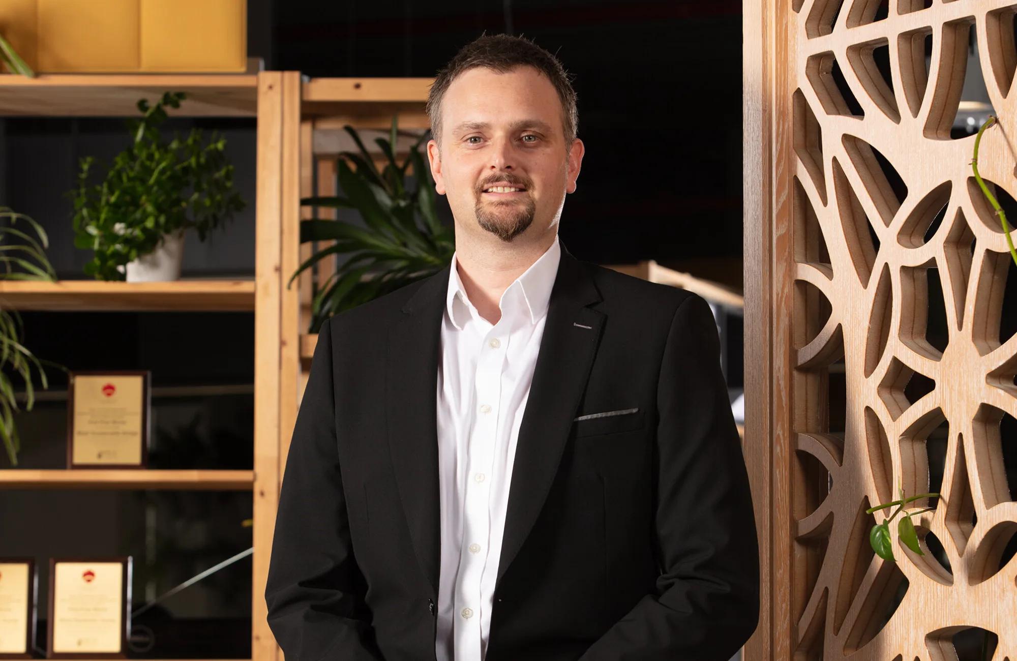 Gary Dodds standing in front a wall with an arabic ornament design in the Cundall Doha office