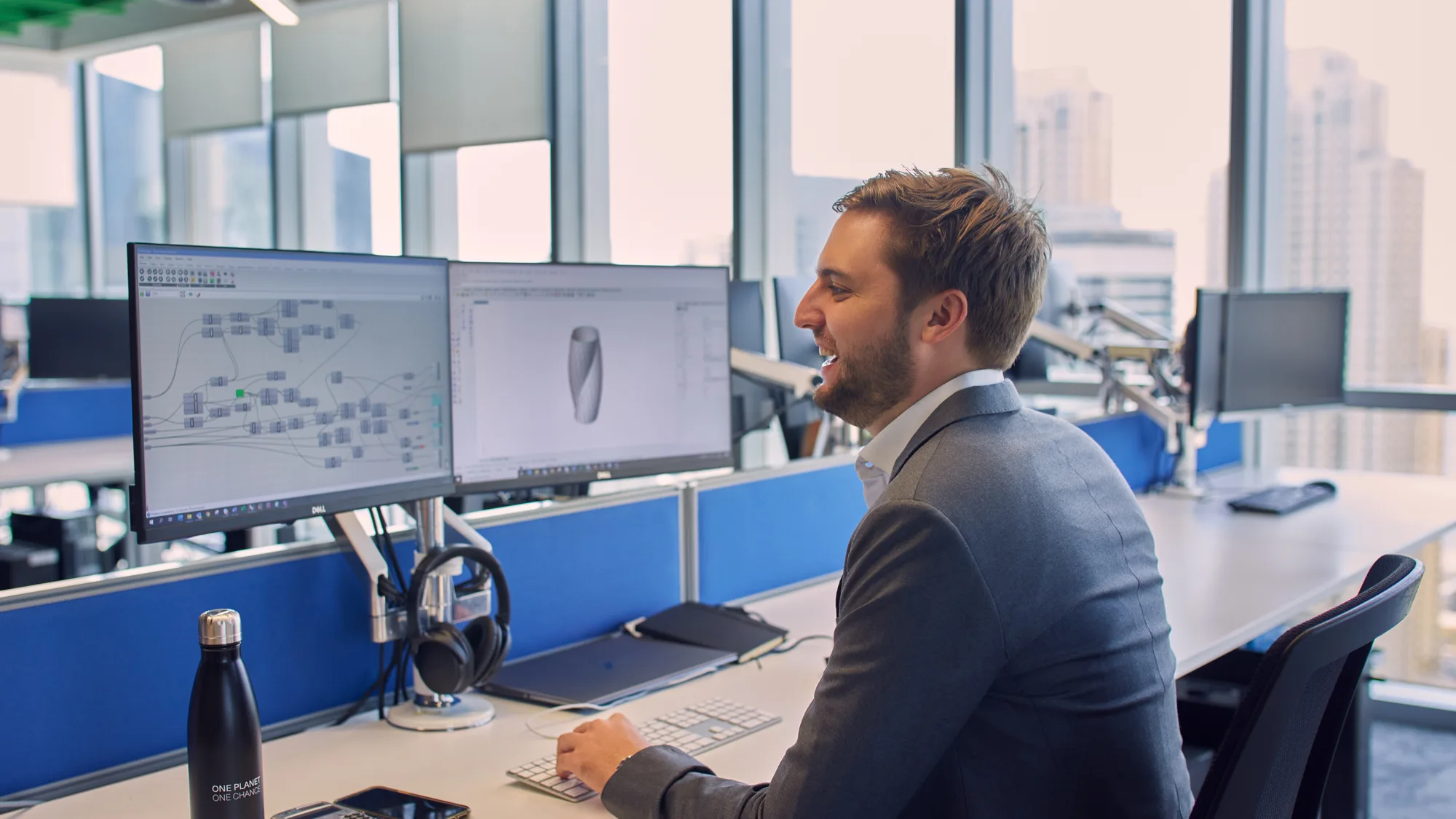 Calum Perey in a suit while happily looking at CAD drawing on screen