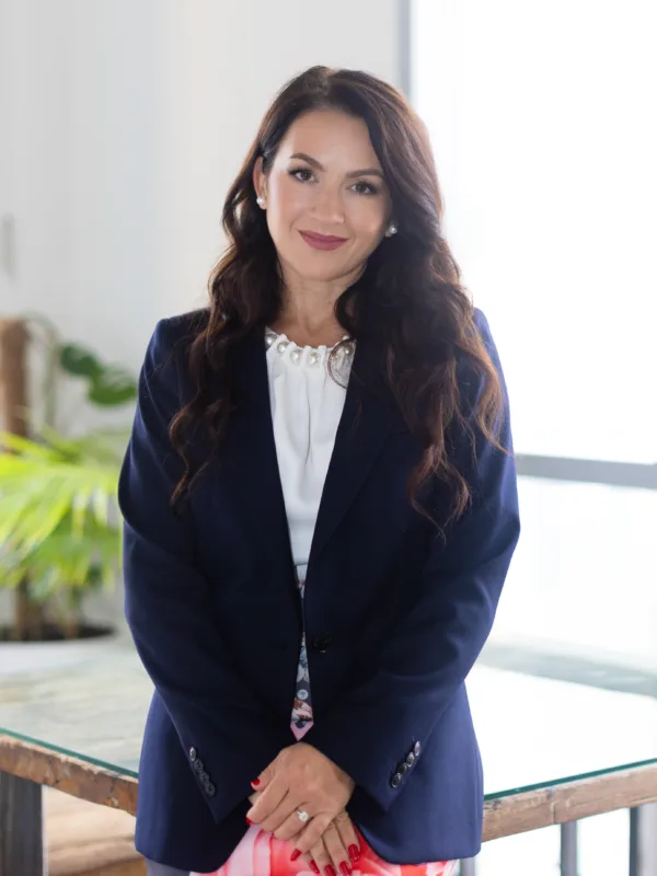 Olga Litkovets in our Dubai office standing in front of a table made out of timbre and glass