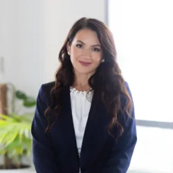 Olga Litkovets in our Dubai office standing in front of a table made out of timbre and glass