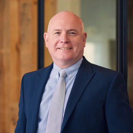 Richard Stratton smiling in-front of the camera with his navy blue suit at our Cundall Dubai WELL office