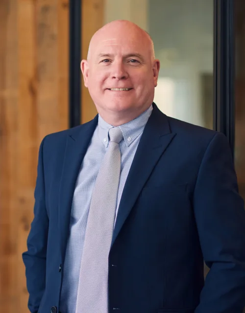 Richard Stratton smiling in-front of the camera with his navy blue suit at our Cundall Dubai WELL office