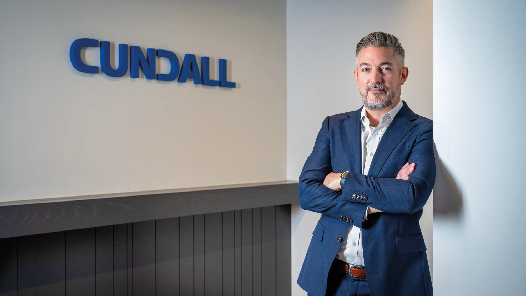 Scott leaning against the wall for a photo in our Dubai office with the Cundall logo at the background.