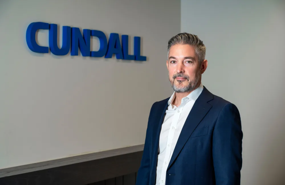 Photo of Scott McKeever in front of Cundall logo signage installed on a white wall