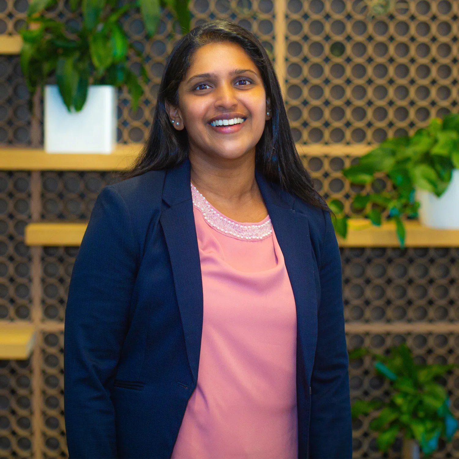 Smitha Mathew smiling with her pink blouse and navy blue coat.