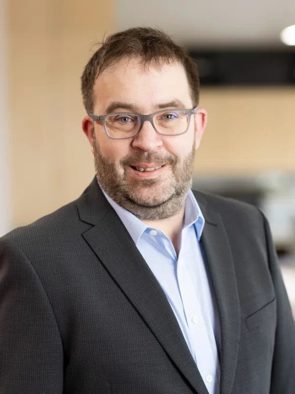 David in an open collar shirt and suit jacket stood in the Dublin office