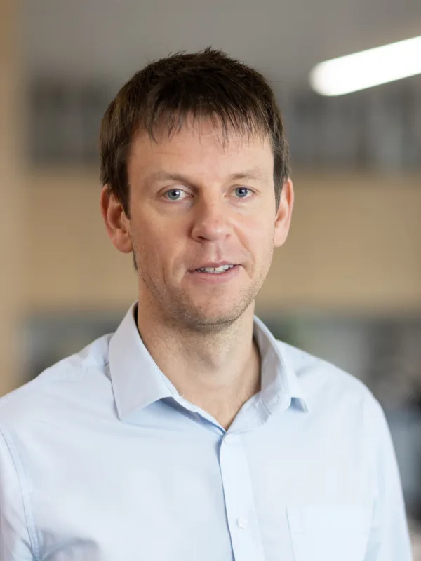 Tom Kennedy smiling in an office wearing a blue shirt