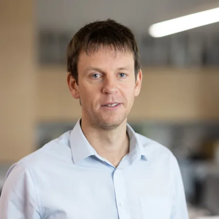 Tom Kennedy smiling in an office wearing a blue shirt