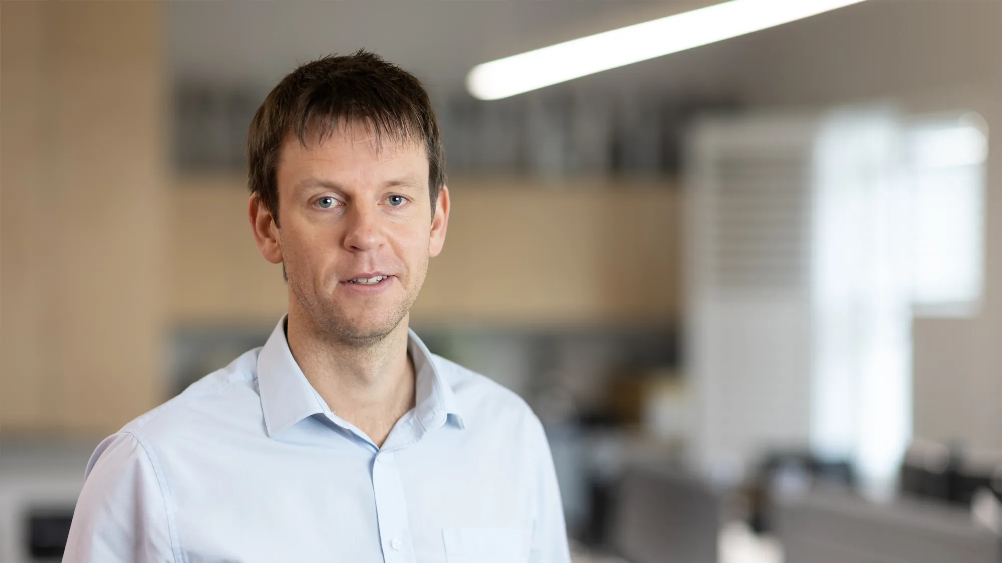 Tom Kennedy smiling in an office wearing a blue shirt