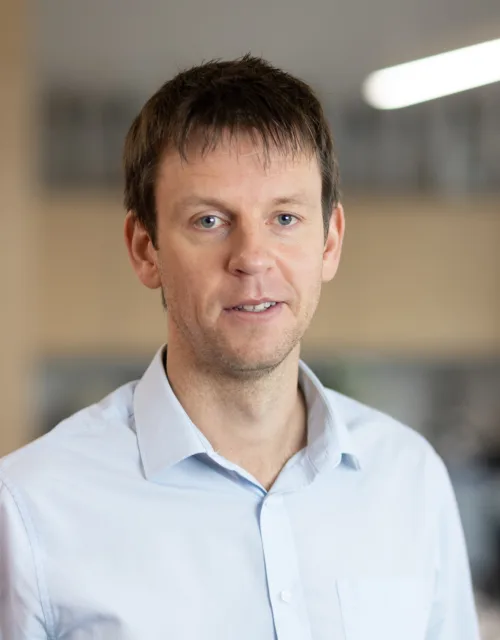 Tom Kennedy smiling in an office wearing a blue shirt