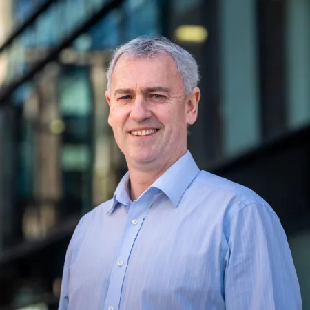 John McLoughlin looking towards the camera in a blue shirt