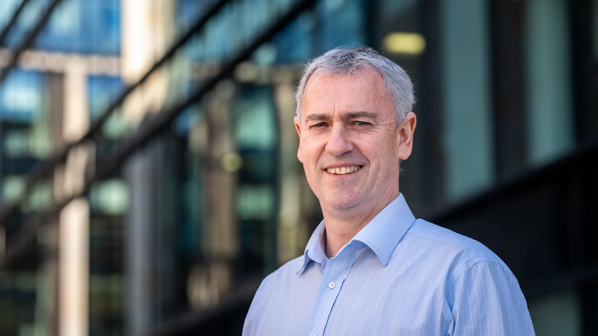 John McLoughlin looking towards the camera in a blue shirt