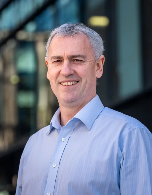 John McLoughlin looking towards the camera in a blue shirt