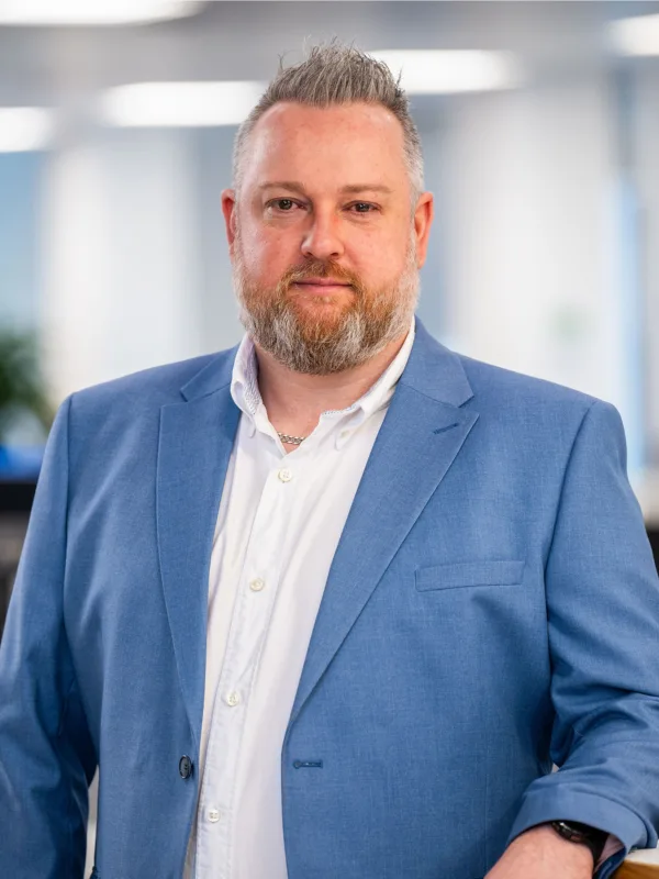 Keith Richardson standing in the Edinburgh office in a white shirt and blue blazer