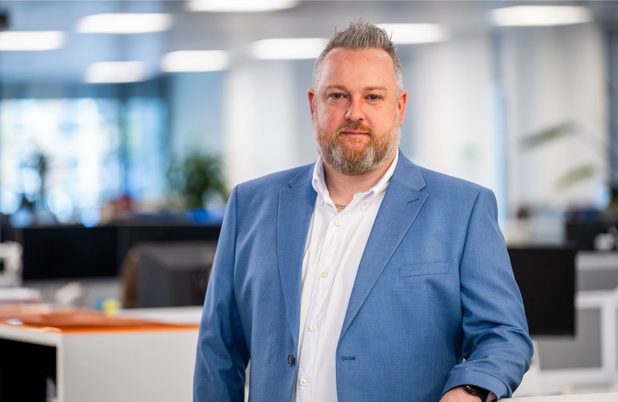 Keith Richardson standing in the Edinburgh office in a white shirt and blue blazer