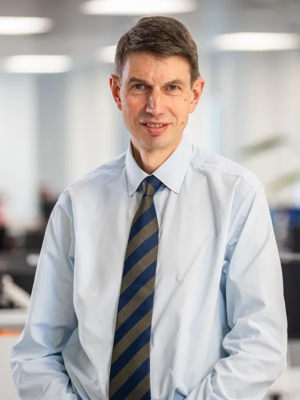 Neil Dely wearing a light blue shirt and striped tie in the Edinburgh office