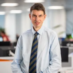 Neil Dely wearing a light blue shirt and striped tie in the Edinburgh office