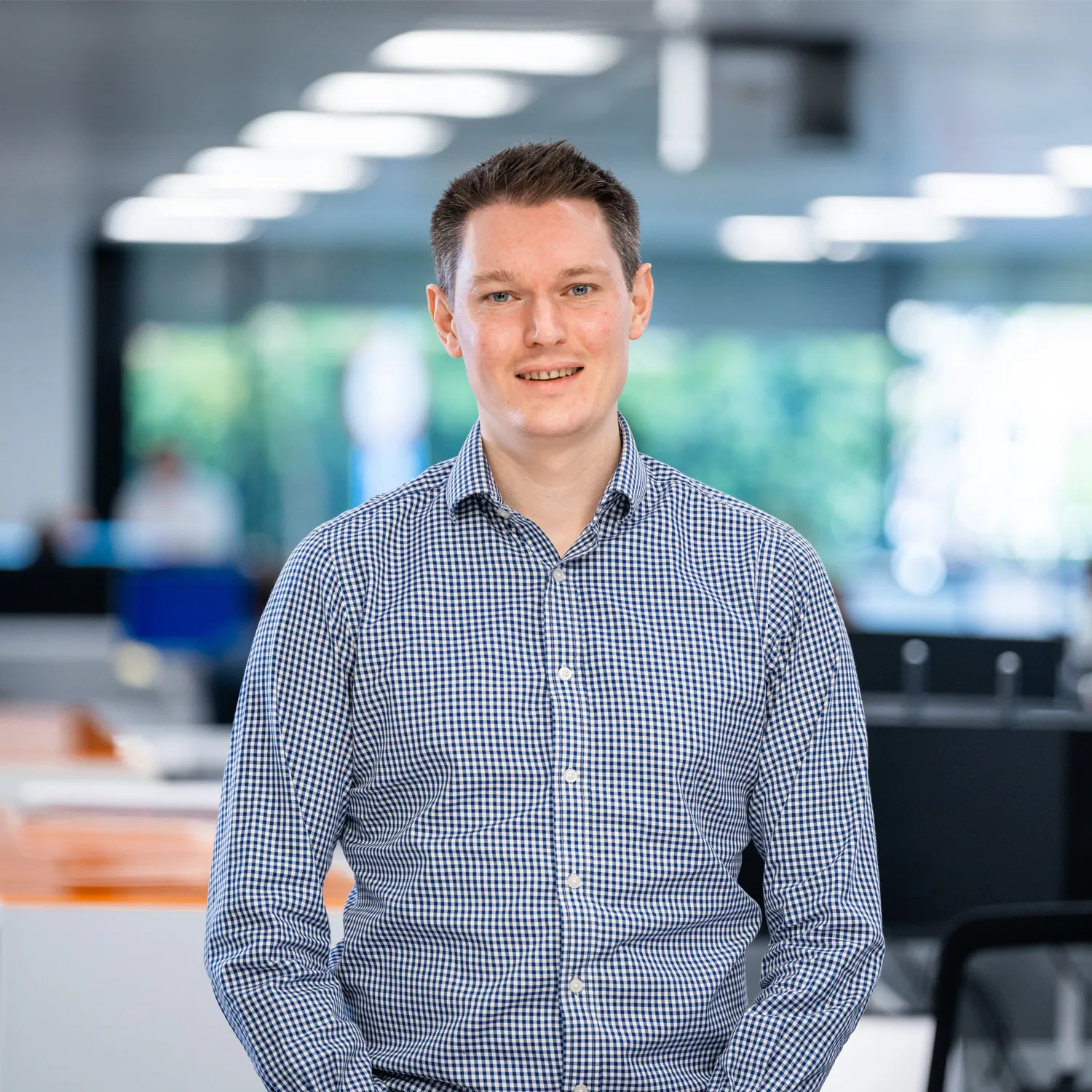 Patrick smiling for a photo with computer monitors and office desks in the background.