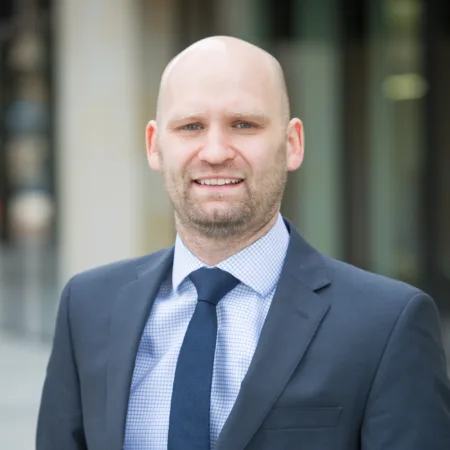 Robert in a suit and navy tie stood outside of the Edinburgh office