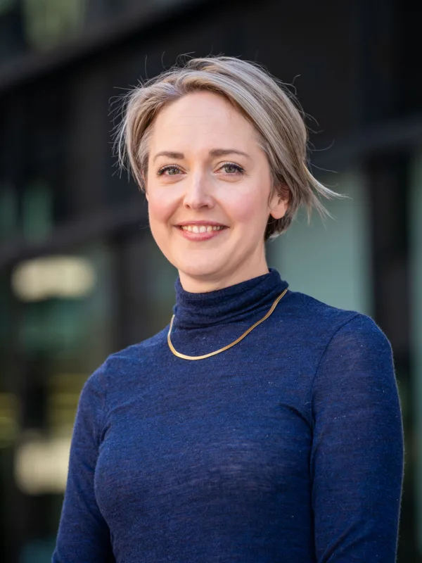 Sophie Simpson smiling looking towards the camera wearing a dark blue top