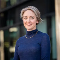 Sophie Simpson smiling looking towards the camera wearing a dark blue top