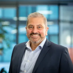 Tony Centola in dark suit with planting and glass office area background blurred