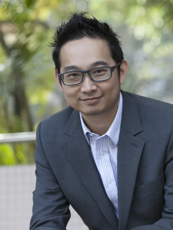 Joe Tang in a grey suit and pale shirt with blurred green park background