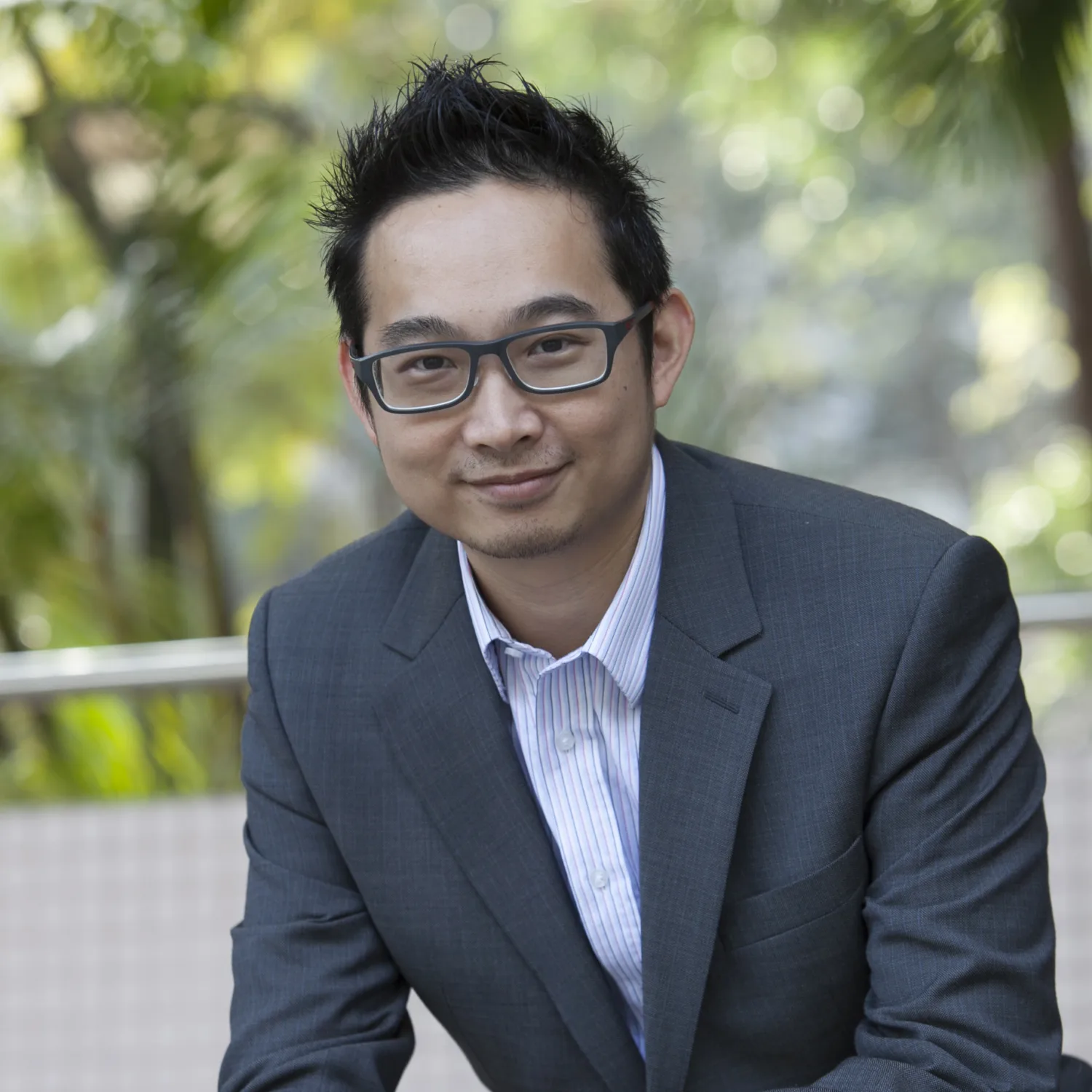 Joe Tang in a grey suit and pale shirt with blurred green park background
