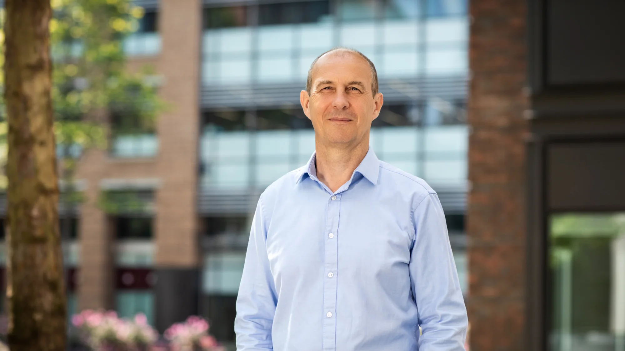 Andrew Moore in front of building with trees and plants in background