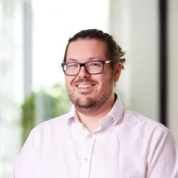 Head and shoulders image of Conrad Stone in an office wearing a white shirt