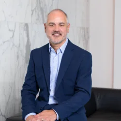 Gary Rollison sitting on sofa arm with marble background