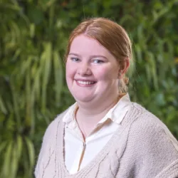 Head and sholders shot of Heater wearing a cream jumper against a background of foliage