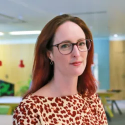 Leigh Harper looking at the camera with an office back drop