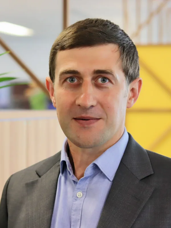 Oleksandr in an open collar shirt and suit jacket in the office space