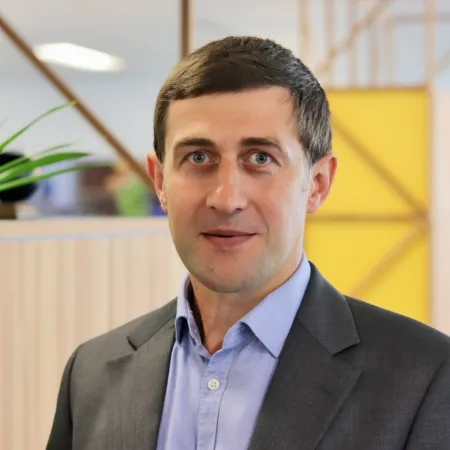 Oleksandr in an open collar shirt and suit jacket in the office space