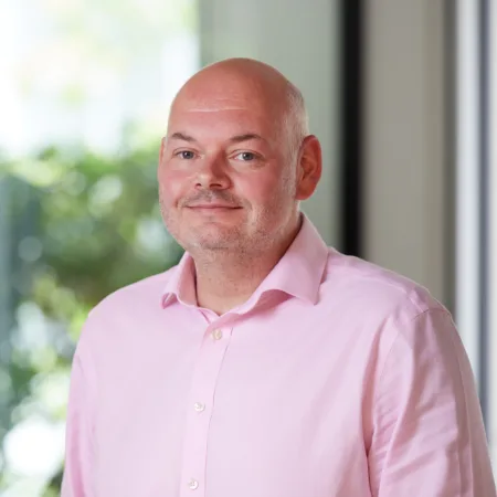 Paul Winstone in a pink shirt in the office reception