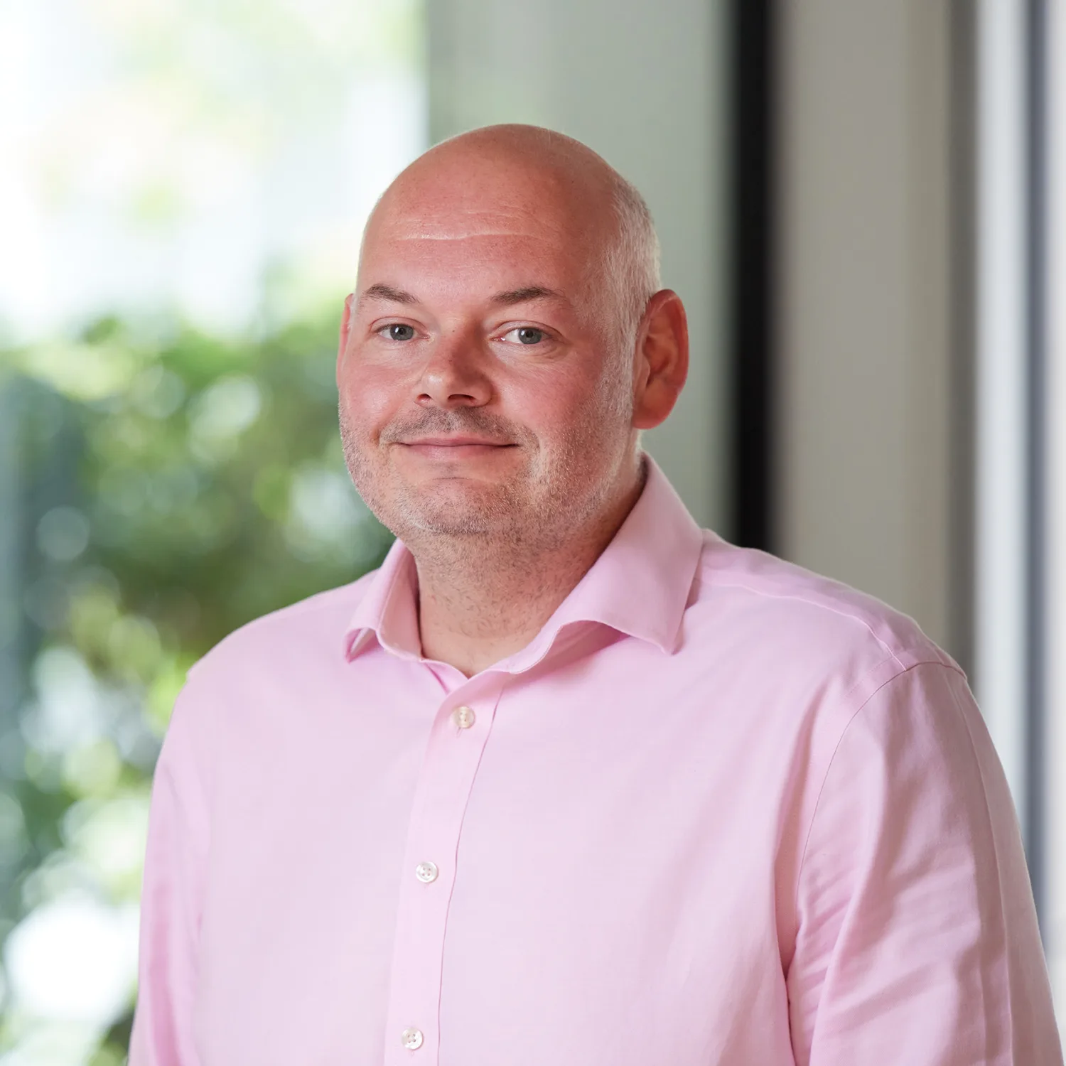 Paul Winstone in a pink shirt in the office reception